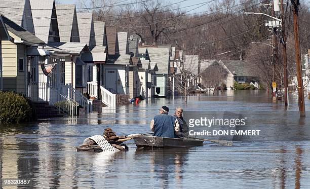 Two men paddle in a row boat on a street filled with floodewaters from the Passaic River on March 16, 2010 in Little Falls, New Jersey. Many...