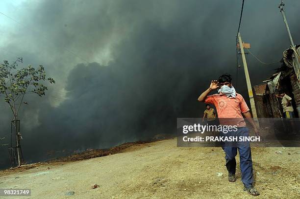 Man walks out of the smoke-engulfed Gazipur slums in New Delhi on April 8, 2010. More than 150 sheds were destroyed in a major fire in the Gazipur...