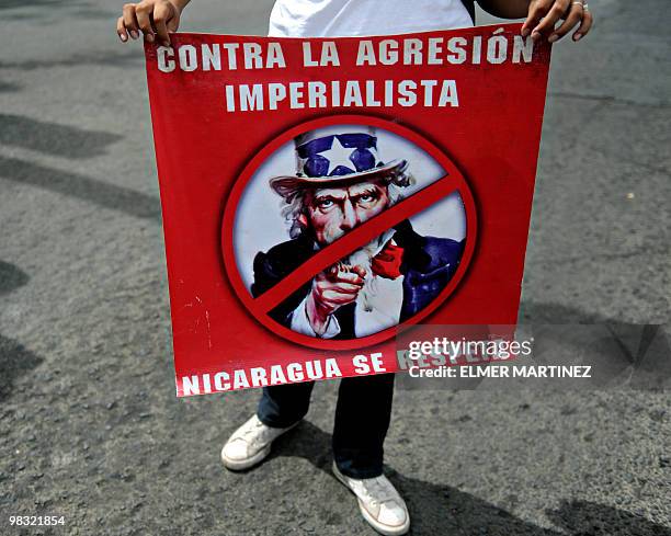 Supporter of Nicaraguan President Daniel Ortega holds a poster against the United States during a violent demonstration in the streets of Managua, on...