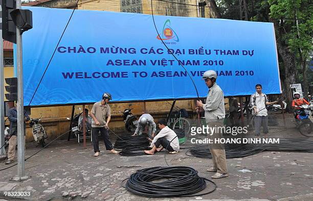 Men work next to a newly installed billboard marking the up-comming 16th summit of the Southeast Asian Nations in Hanoi on April 5, 2010. The two-day...