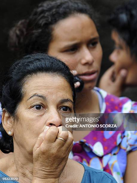 Residents of Vicoso Jardim shantytown react as firefighters and rescue workers search for victims following a landslide in Vicoso Jardim shantytown...
