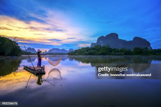 silhouette fisherman fishing nets on the boat.thailand - krabi province stock-fotos und bilder