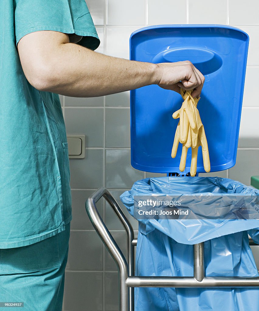 Surgeon throwing used rubber gloves into bin