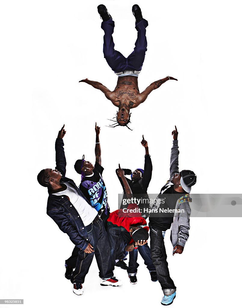 Hip hop dancer performing stunt with his friends pointing at him