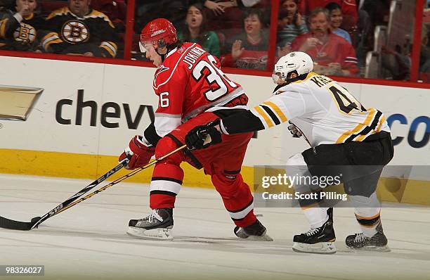 David Krejci of the Boston Bruins reaches in to attempt to knock the puck from Jussi Jokinen of the Carolina Hurricanes during their NHL game on...