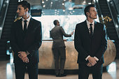 two bodyguards waiting for businessman standing at reception counter