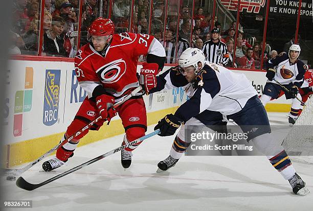 Patrick Dwyer of the Carolina Hurricanes skates the puck along the boards against the defense of Zach Bogosian of the Atlanta Thrashers during their...