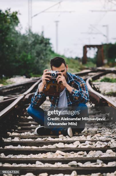 young hipster guy tourist with camera and bag photographing on t - camera bag stock-fotos und bilder