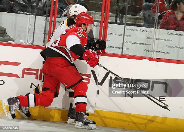 Tuomo Ruutu of the Carolina Hurricanes checks one of the Boston Bruins into the boards during their NHL game on March 16, 2010 at the RBC Center in...