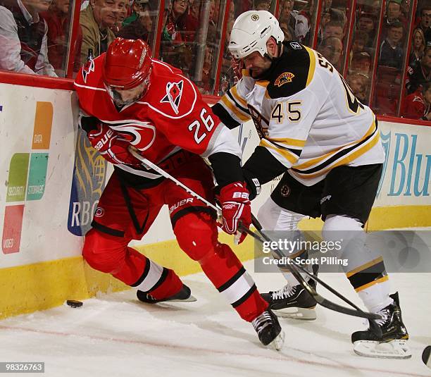 Erik Cole of the Carolina Hurricanes battles for the puck along the boards with Mark Stuart of the Boston Bruins during their NHL game on March 16,...