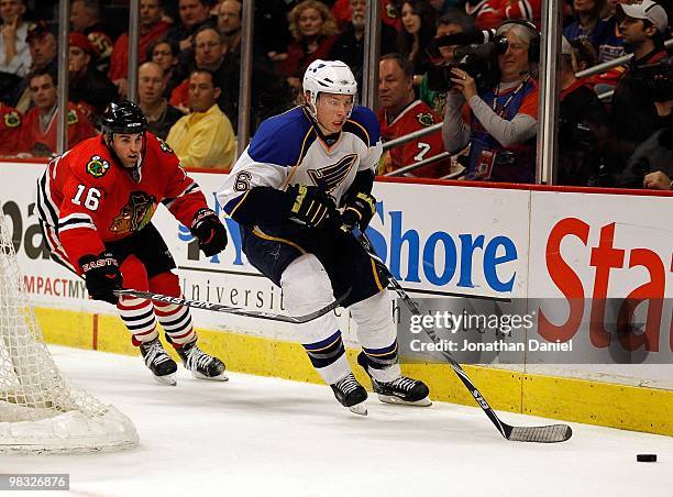 Erik Johnson of the St. Louis Blues chases down the puck pursued by Andrew Ladd of the Chicago Blackhawks at the United Center on April 7, 2010 in...