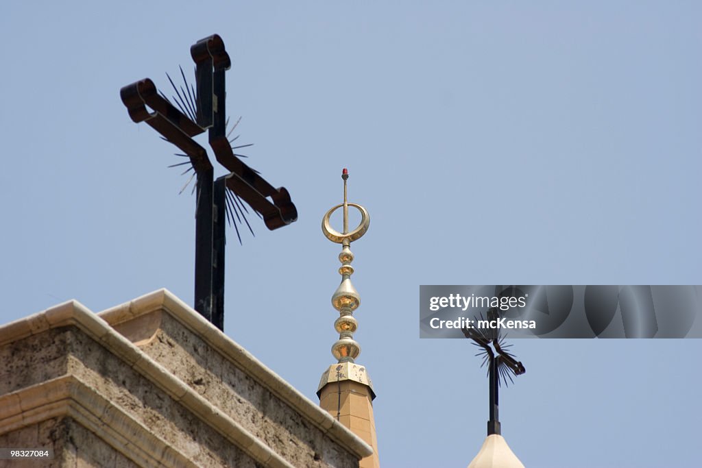 Two Christian crosses, one Islamic spire against blue sky