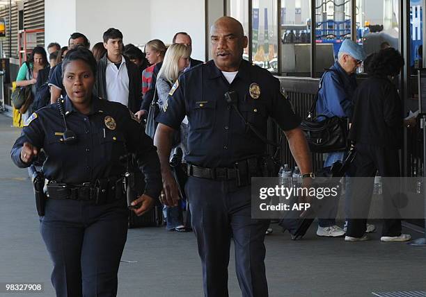 Airport police keep watch as United Airlines passengers wait outside a terminal seven security checkpoint at Los Angeles International Airport after...