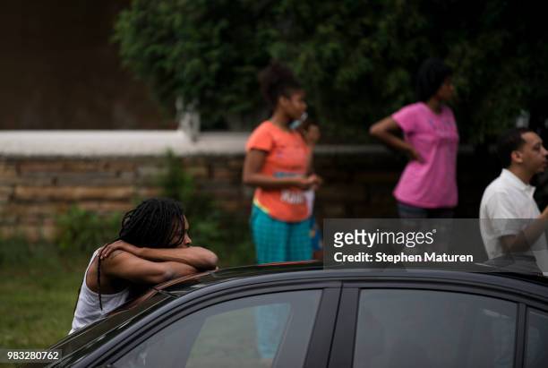 Man leans on his car and listens to speakers at a vigil for Thurman Blevins on June 24, 2018 in Minneapolis, Minnesota. Blevins was shot and killed...