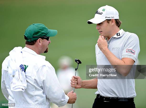 Nick Watney hands his putter to his caddie Tim Goodell on the second green during the first round of the 2010 Masters Tournament at Augusta National...