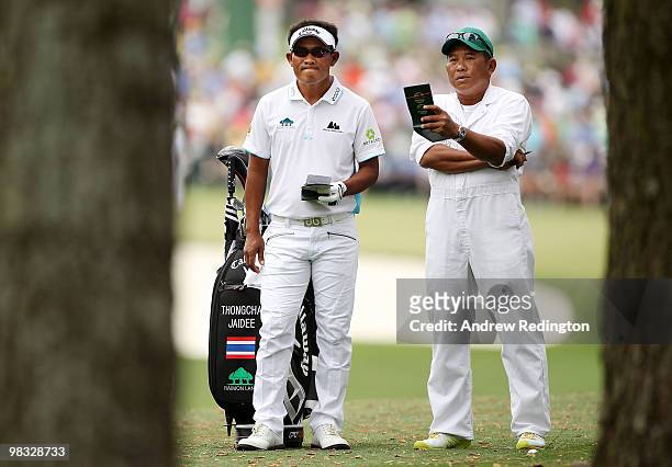 Thongchai Jaidee of Thailand talks with his caddie Surawut Wannapintu on the first hole during the first round of the 2010 Masters Tournament at...