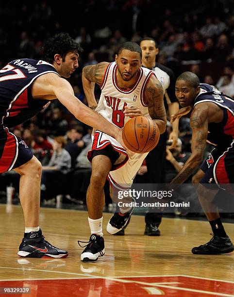 Acie Law of the Chicago Bulls drives between Zaza Pachulia and Jamal Crawford of the Atlanta Hawks at the United Center on March 1, 2010 in Chicago,...