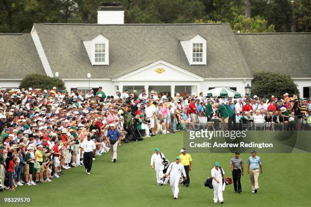 Tiger Woods, Matt Kuchar and K.J. Choi of Korea walk off the first tee with their caddies during the first round of the 2010 Masters Tournament at...