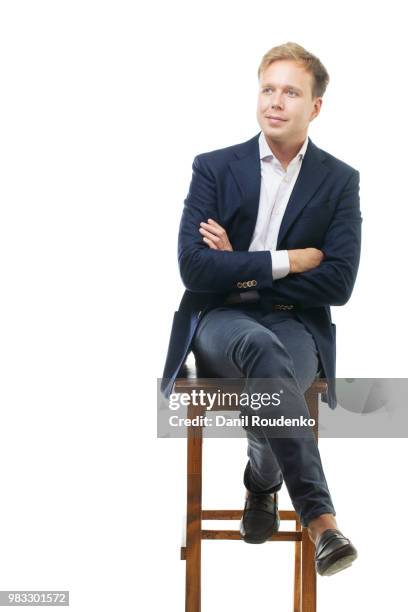 young businessman sitting on high wooden chair - directors chair stock pictures, royalty-free photos & images