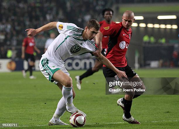 Edin Dzeko of Wolfsburg and Paul Konchesky of Fulham compete for the ball during the UEFA Europa League quarter final second leg match between VfL...