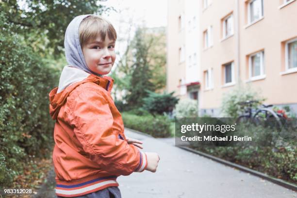 portrait of a five year old boy in rainy autumn weather, urban background - michael virtue stock pictures, royalty-free photos & images