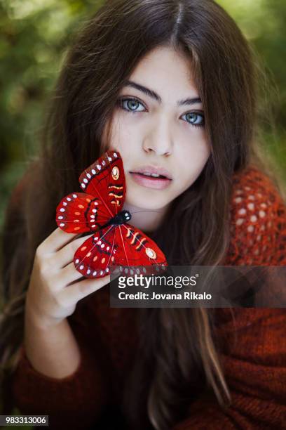 portrait of teenage girl (16-17) holding red artificial butterfly - jovanat stock pictures, royalty-free photos & images