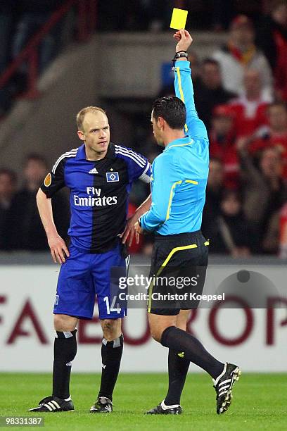 Referee Pedro Oliveira Alves Garcia shows David Jarolim of Hamburg the yellow card during the UEFA Europa League quarter final second leg match...