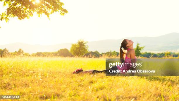 young athletic woman practicing yoga on a meadow at sunset, image with lens flare - relaxed sunshine happy lens flare bildbanksfoton och bilder