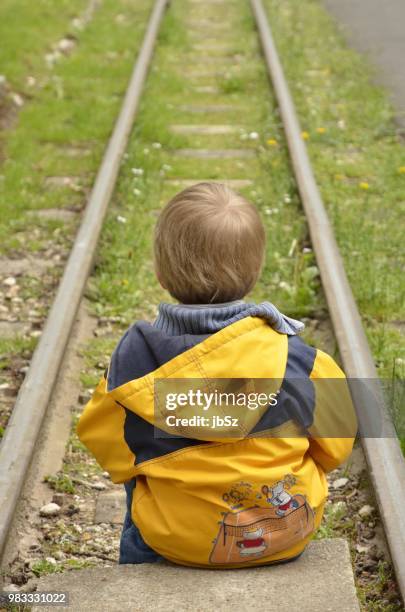 enfant assis face aux rails - enfant stock-fotos und bilder