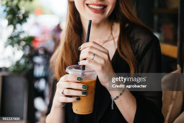 smiling woman drinking iced coffee - iced coffee stock pictures, royalty-free photos & images