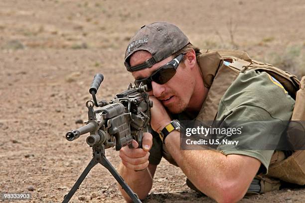 In this handout provided by the U.S. Navy, New Orleans Saints quarterback Drew Brees looks through the sights of an M249 Squad Automatic Weapon...