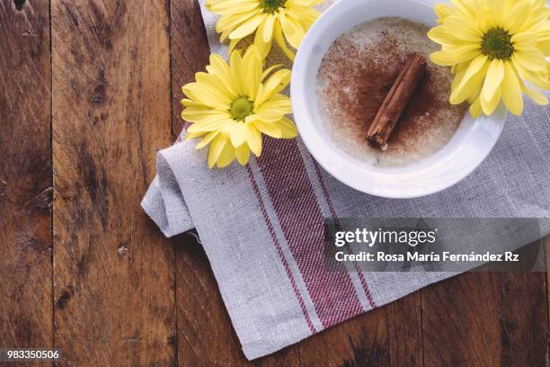 directly above of bowl of milk rice pudding sprinkle with cinnamon, cinnamon stick and three daisies on rustic wooden background. copy space - rz fotografías e imágenes de stock