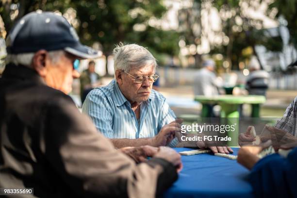 active retirement happy old friends playing domino game - dominó imagens e fotografias de stock
