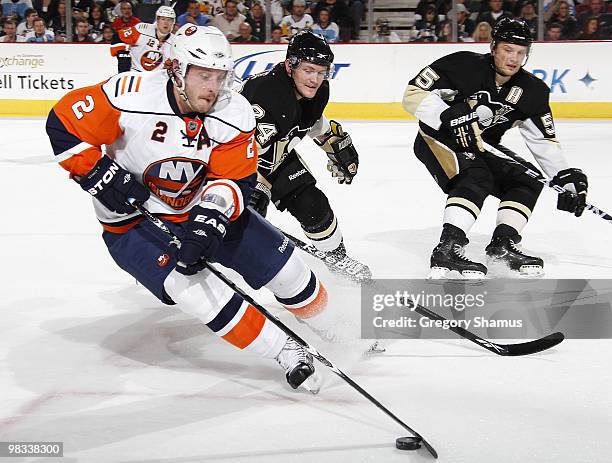 Mark Streit of the New York Islanders moves the puck in front of Matt Cooke and Sergei Gonchar of the Pittsburgh Penguins on April 8, 2010 at Mellon...