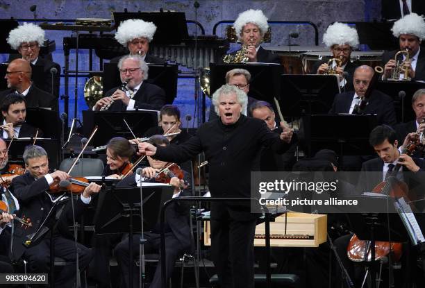 June 2018, Germany, Berlin: Sir Simon Rattle conducting musicians, some of whom are wearing wigs, during his last concert with the Berliner...