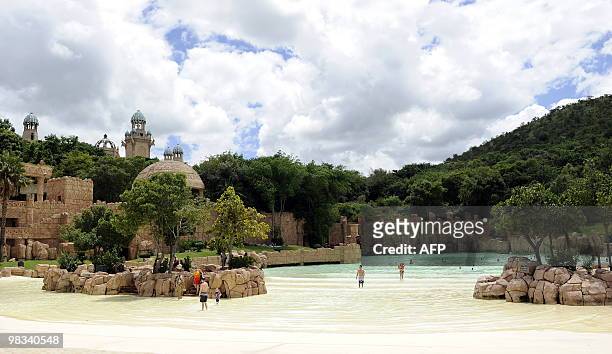 People bath in the artificial sandy beach of the Lost City water park in Sun City on February 22, 2010. The shaking walkway -- leading to a man-made...