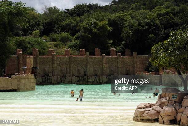 People bath in the artificial sandy beach of the Lost City water park in Sun City on February 22, 2010. The shaking walkway -- leading to a man-made...