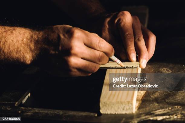 a man talking measurements on a piece of wood. - obradovic stock pictures, royalty-free photos & images