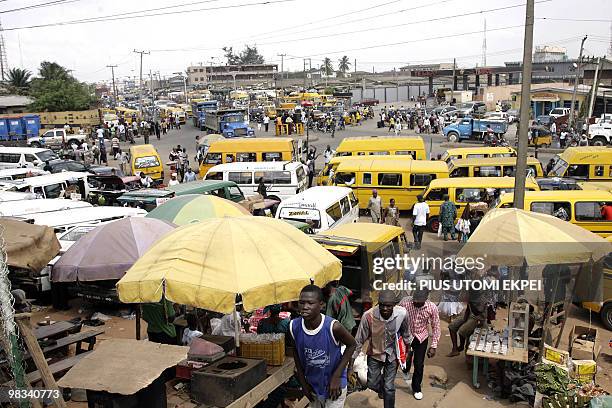 Sonia BAKARIC Passers-by walk past street vendors selling their wares at Ojodu Motor Park in Lagos on April 7, 2010. Despite the effort being made by...