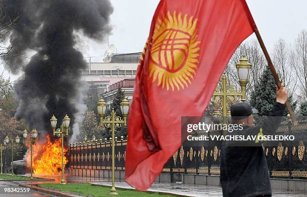 Kyrgyz opposition supporter waves the national flag near the main government building during an anti-government protest in Bishkek on April 7, 2010....