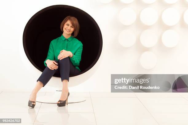 attractive woman sitting on spherical chair with hands on knees - standing with hands on knees imagens e fotografias de stock