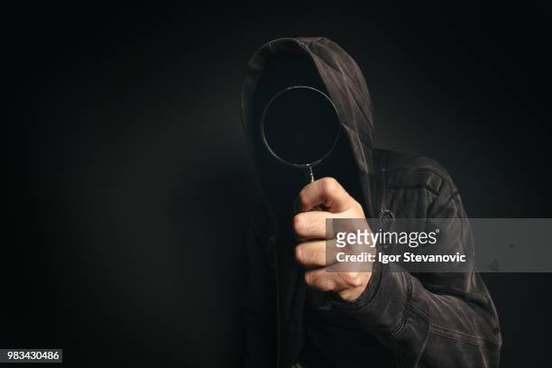 spyware computer software, hooded spooky person with magnifying - android malware stockfoto's en -beelden