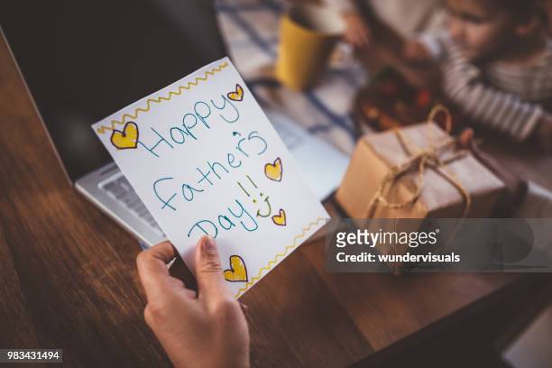 working at home father holding father's day card and gift - fathers day stock pictures, royalty-free photos & images