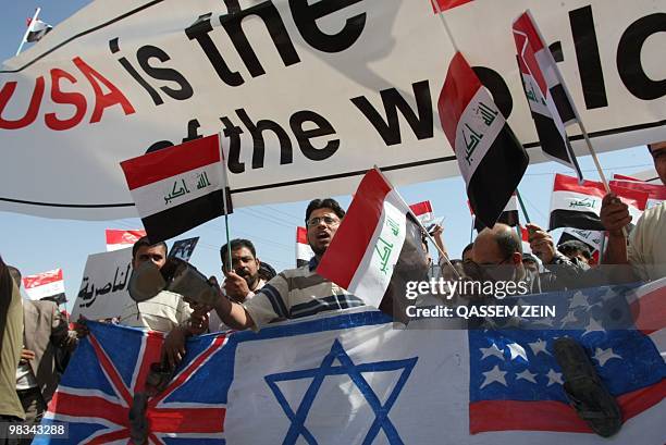 Demonstrators carry Iraqi flags and mock US, Israeli, and UK flags during a demonstration in the Shiite holy city of Najaf on April 9, 2010. Called...