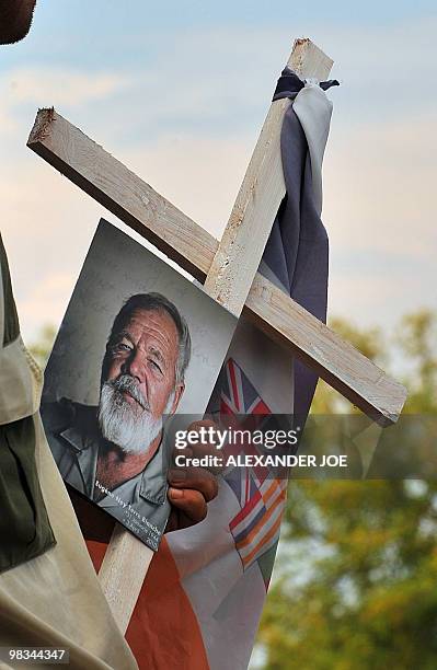 Afrikaner Resistance Movement member holds a picture of AWB leader Eugene Terre'Blanche and an AWB flag tied to a cross during his funeral at a...