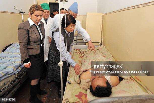 Kyrgyz interim leader Roza Otunbayeva looks at a patient injured during the April 7 anti-government riots in a Bishkek hospital on April 9, 2010....