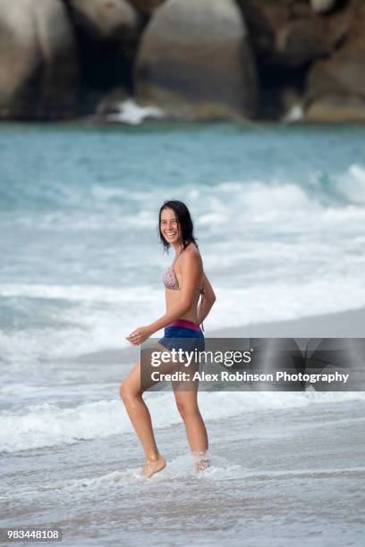 a young woman wearing a bikini on a deserted tropical beach in colombia, having fun in nature - マグダレーナ ストックフォトと画像