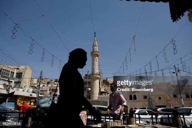Woman passes a street vendor and a minaret in Amman, Jordan, on Thursday, June 21, 2018. President Trump and First Lady Melania Trump will host...