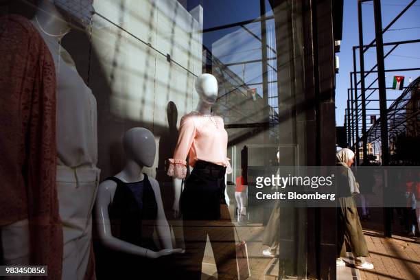 Pedestrian passes fashion mannequins in the window of a clothing store in the Sweifieh district of Amman, Jordan, on Thursday, June 21, 2018....