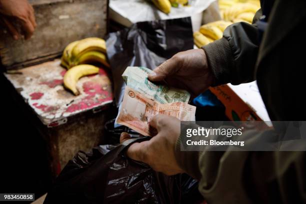 Man counts out Jordanian dinar banknotes at a local fruit and vegetable market in Amman, Jordan, on Thursday, June 21, 2018. President Trump and...